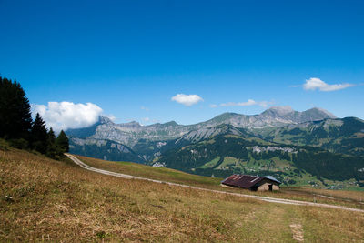 Scenic view of field by mountains against blue sky