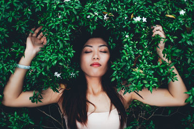 Young woman against plants