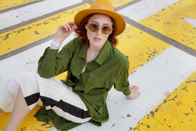 Young woman sitting on yellow umbrella