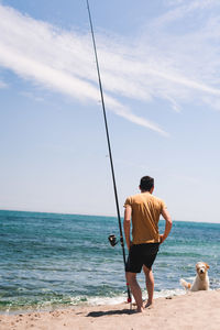 Rear view of man fishing on beach