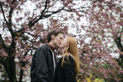 Beautiful woman standing by flowers against tree