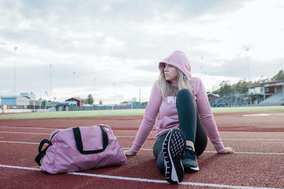 Woman sat on a running track looking thoughtful