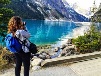 Rear view of man photographing on lake