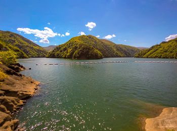 Scenic view of lake by mountains against sky