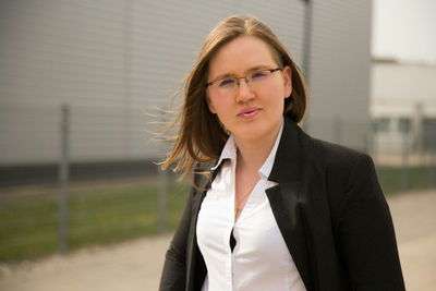Portrait of businesswoman wearing eyeglasses while standing against building