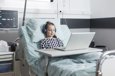 Patients with oxygen tube looking at laptop in hospital