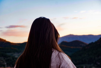 Rear view of woman looking at mountains against sky