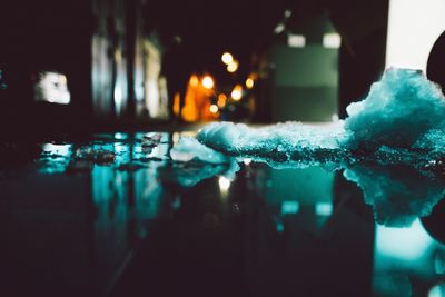 Reflection of buildings on water by ice in street at night