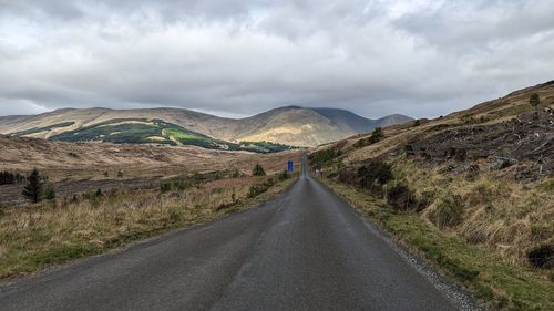 Road amidst field against sky