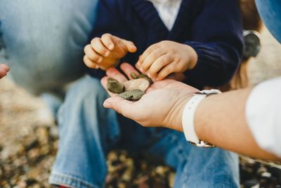 Midsection of boy holding pebbles from hand