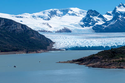 Scenic view of sea and snowcapped mountains against sky