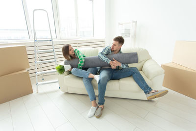 Full length of man sitting on sofa at home