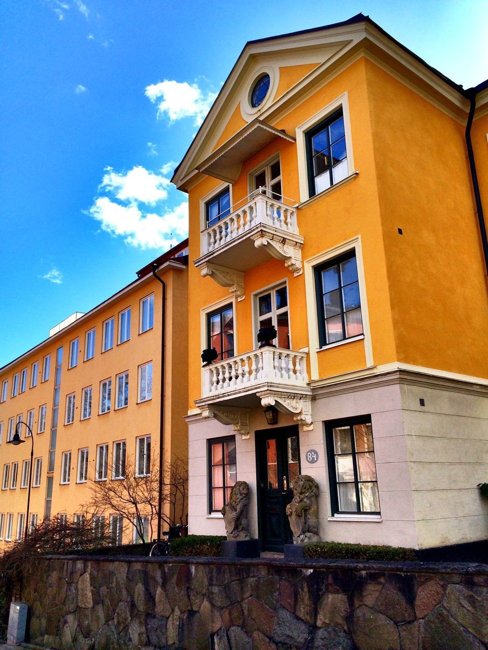 architecture, building exterior, built structure, window, low angle view, residential building, building, residential structure, sky, balcony, yellow, day, outdoors, house, city, facade, no people, sunlight, brick wall, shadow