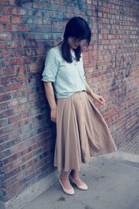 Full length of woman standing against brick wall