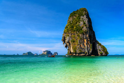 Scenic view of rock formation in sea against blue sky