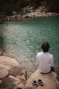 Rear view of woman sitting at lakeshore