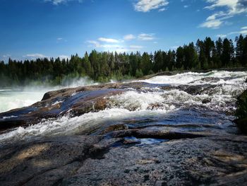Scenic view of waterfall in forest against sky