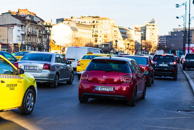 Traffic on city street by buildings against sky