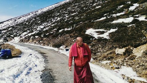 Woman walking on snow covered mountain against sky