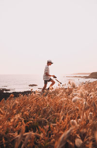 Side view of man standing on beach against clear sky