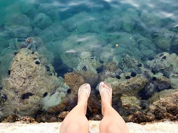 Low section of woman legs on rock at beach
