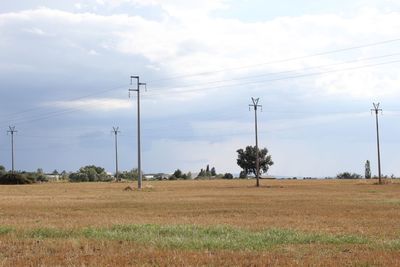 Electricity pylon on field against sky