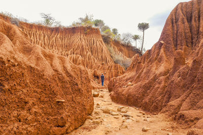 Rear view of man standing on rock formations at ol jogi canyons, nanyuki, kenya 