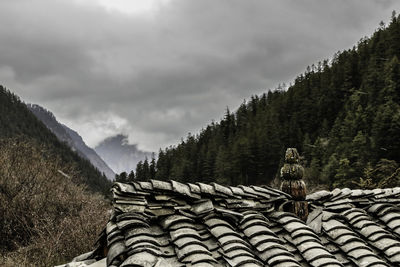 Low angle view of house by mountain against cloudy sky