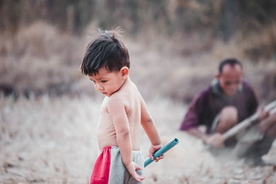 Cute boy looking away while standing on field