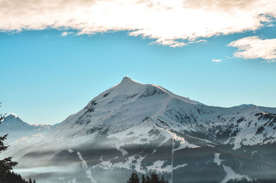 Scenic view of snow covered mountains against blue sky