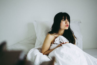 Young woman sitting on bed at home