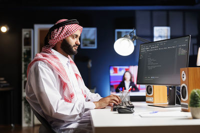 Rear view of woman using digital tablet while standing in office