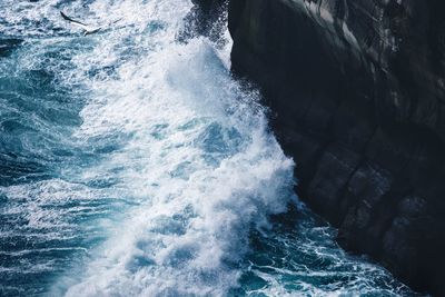 High angle view of waves splashing on rocks