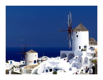 Traditional windmill by building against blue sky