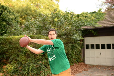 Man holding ball in yard against clear sky