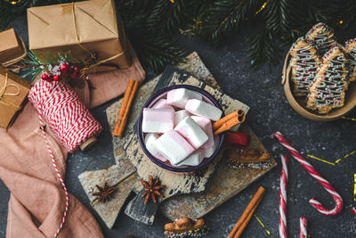 One red mug with hot cocoa, marshmallows on top with cinnamon, gingerbread man on a cutting board 