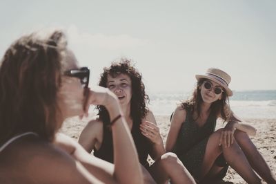 Portrait of smiling young woman on beach against sky