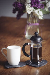 Coffee cup and french press on table