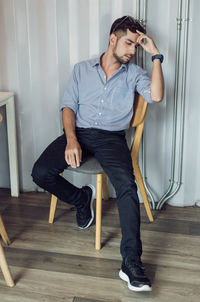 Young man looking away while sitting on chair