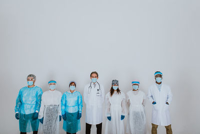 Portrait of doctors wearing mask standing against white background