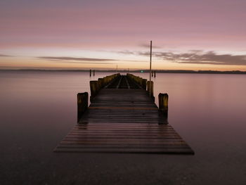 Pier over sea against sky during sunset