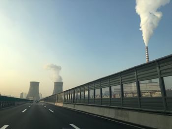 Smoke emitting from factory against sky