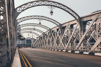 Lanterns hanging over metallic bridge against sky