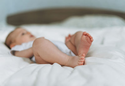 Cute baby girls 2-4 month on bed, natural tones, focus on legs