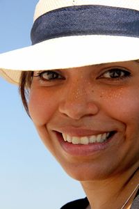 Close-up portrait of smiling young woman against gray background