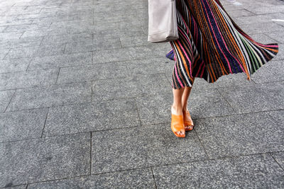 Low section of woman standing on footpath