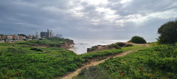 Scenic view of sea, cliff  and buildings against sky