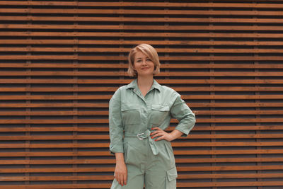 Portrait of smiling young woman standing against brick wall