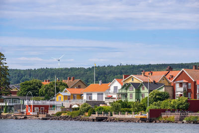 Houses by river and buildings against sky