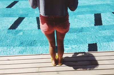 Low section of woman standing in swimming pool